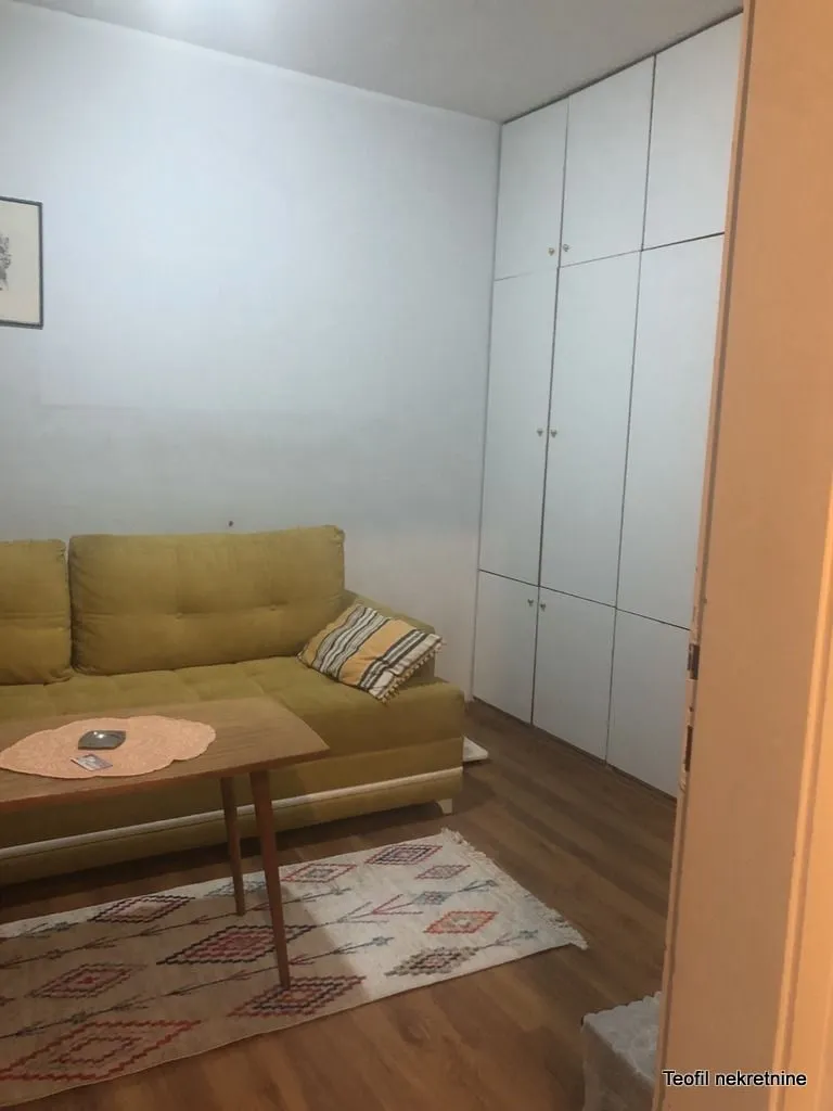 Manja dnevna soba sa žutim kaučem, stočićem i ugradnim garderoberom.
