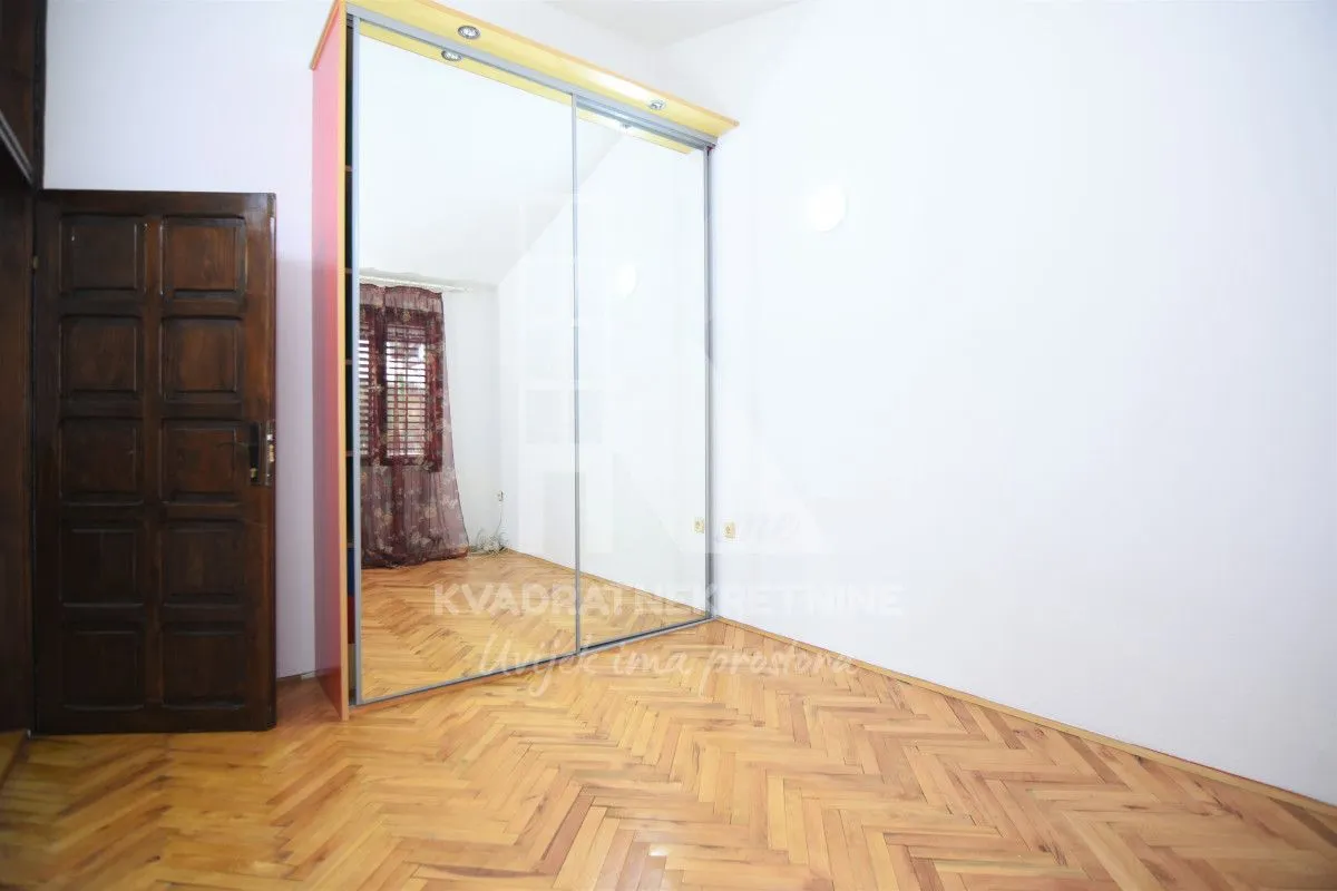 Empty bedroom with a large fitted mirrored wardrobe and hardwood flooring.