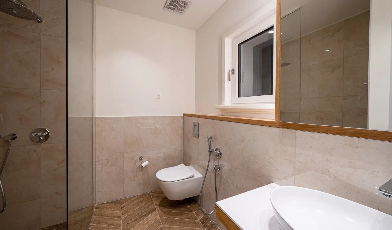 Savremeno opremljeno kupatilo sa tuš kabinom, umivaonikom i WC šoljom.