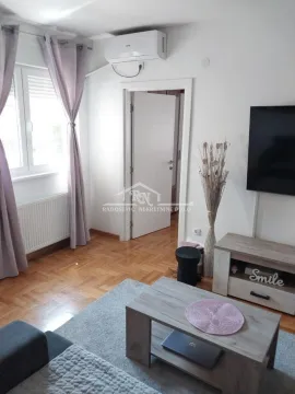 Living room with a sofa, TV, and wooden flooring. - image 3