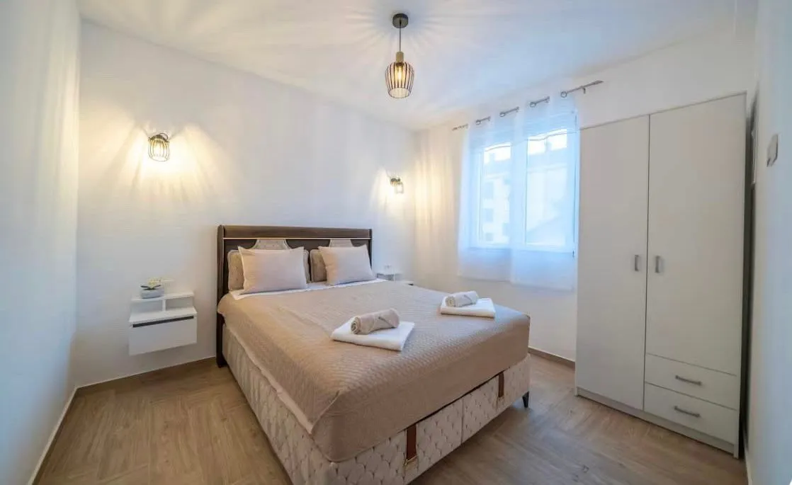 Bright bedroom featuring a double bed and a large white wardrobe.