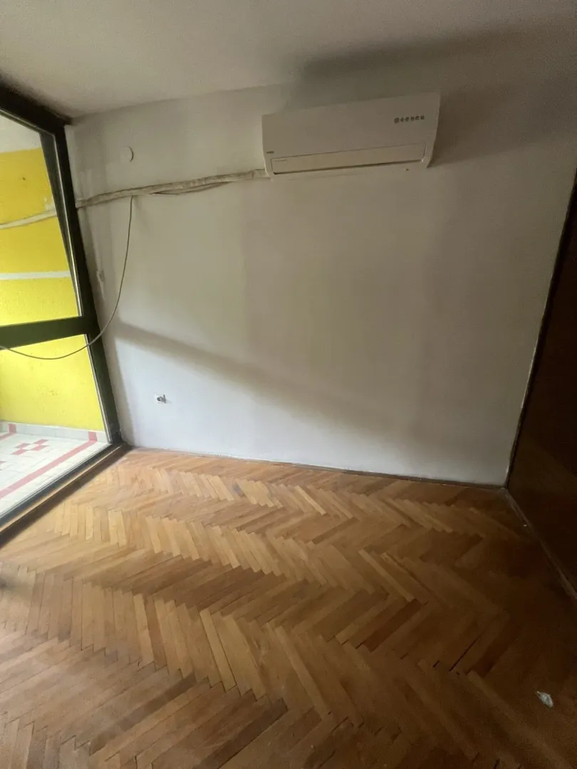 Prazna soba sa parketom i klima uređajem.