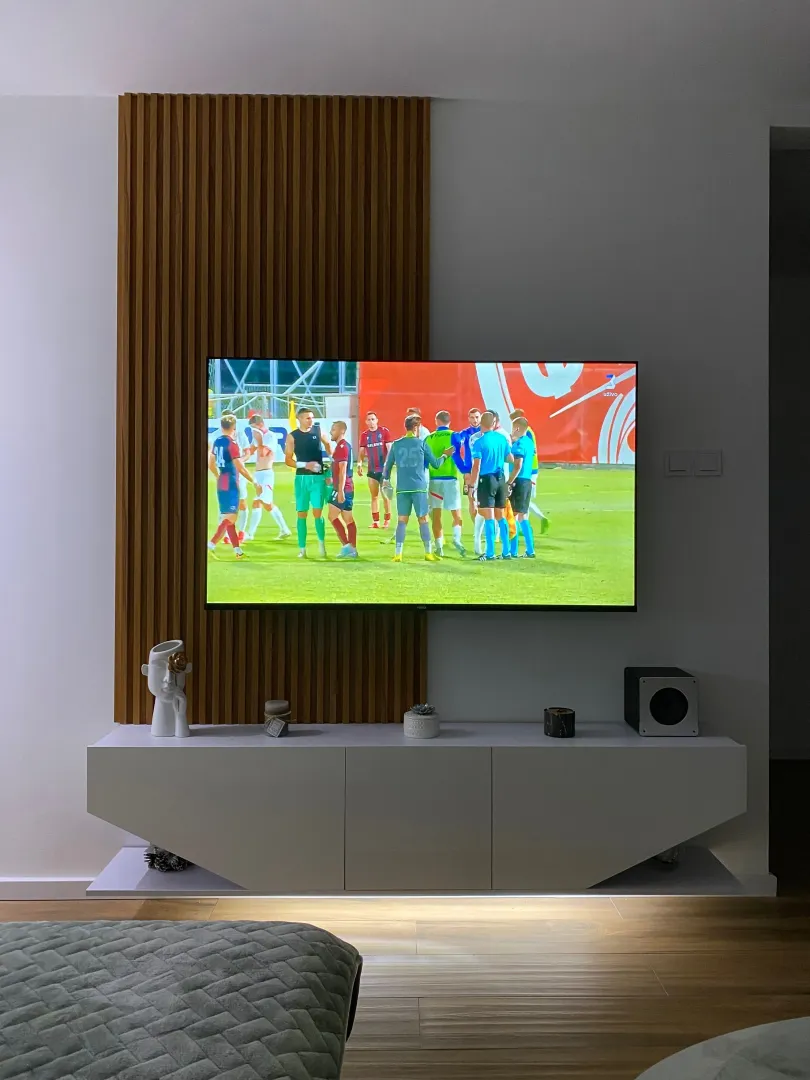 Living room with a wall-mounted TV featuring wooden panels and a media console.