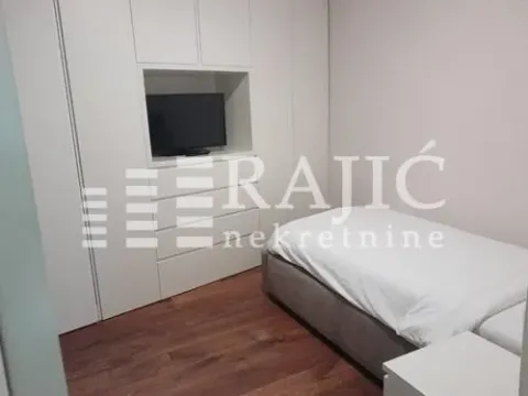 Smaller bedroom with a bed and a built-in wardrobe with a television. - image 5