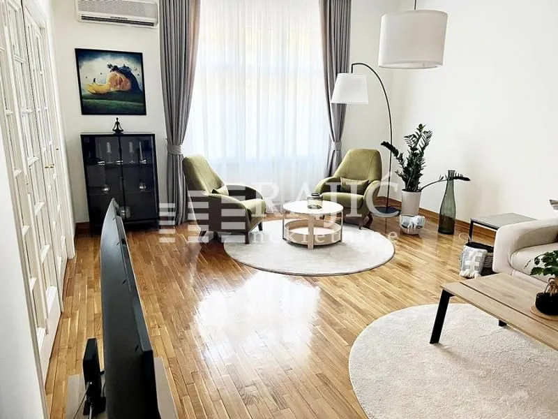 Spacious and bright living room with seating area and parquet flooring.