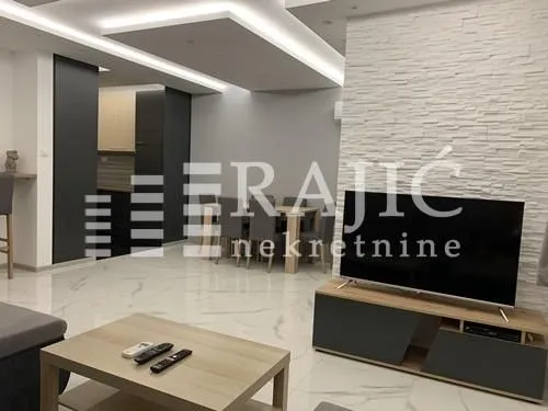 Living room with sofa, dining area, and kitchen in the background.