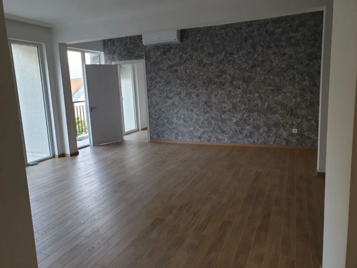 Spacious empty room with a decorative grey wall and laminate flooring.
