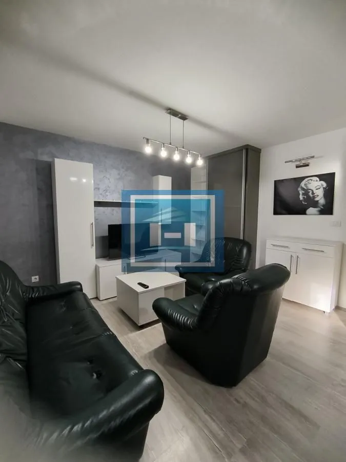 Nameštena dnevna soba sa garniturom za sedenje i TV komodom.