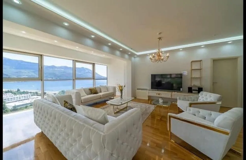 Spacious living room with seating area, TV, and large windows with a sea view.