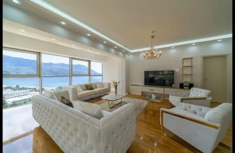 Spacious living room with seating area, TV, and large windows with a sea view. - image 7