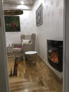 A cozy seating corner with a comfortable armchair and an electric fireplace. - image 7