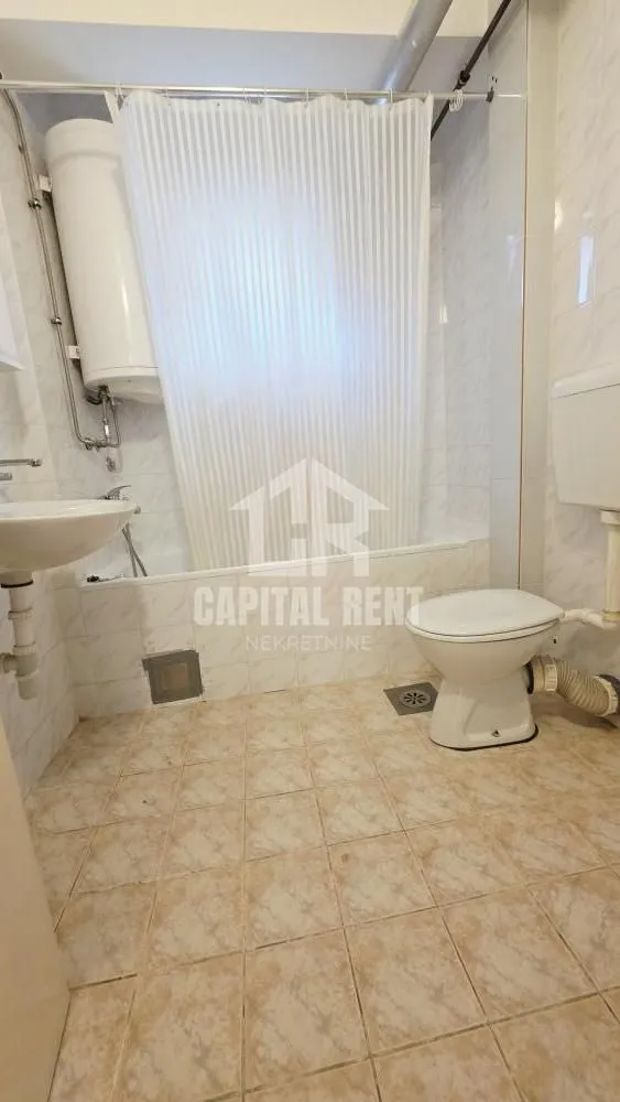 Bathroom with a bathtub, sink, toilet, and water heater.
