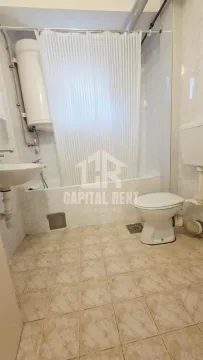 Bathroom with a bathtub, sink, toilet, and water heater. - image 9