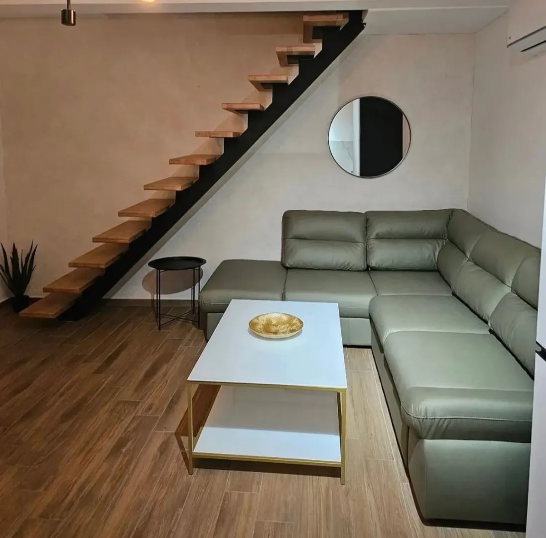 Living room with a corner sofa, coffee table, and staircase.