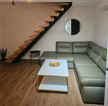 Living room with a corner sofa, coffee table, and staircase. - image 2