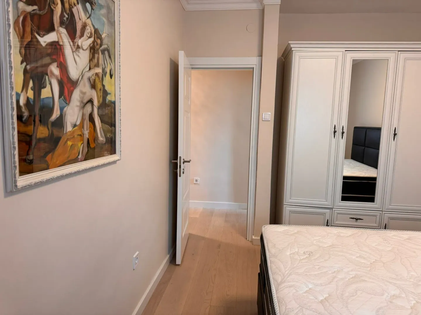 Bedroom with a large wardrobe, bed, and an artwork on the wall.