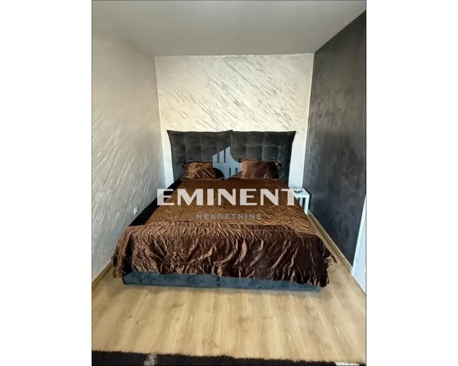 A bedroom with a large double bed and decorative wall finishes.