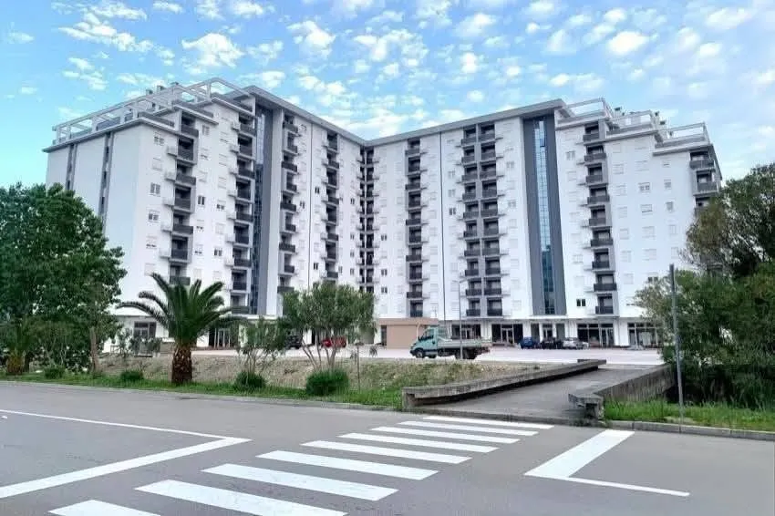 Pogled na spoljašnjost moderne stambene zgrade sa uređenim dvorištem.
