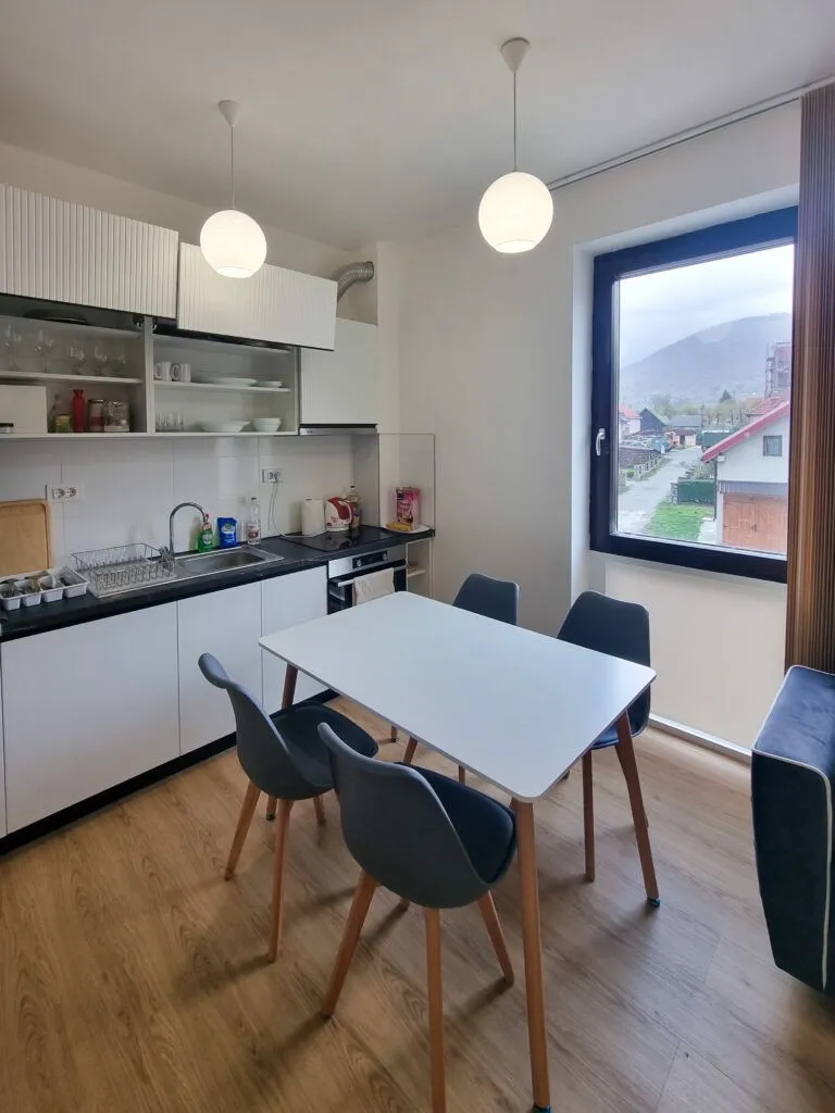 Moderna kuhinja sa trpezarijskim stolom i pogledom na okolinu.