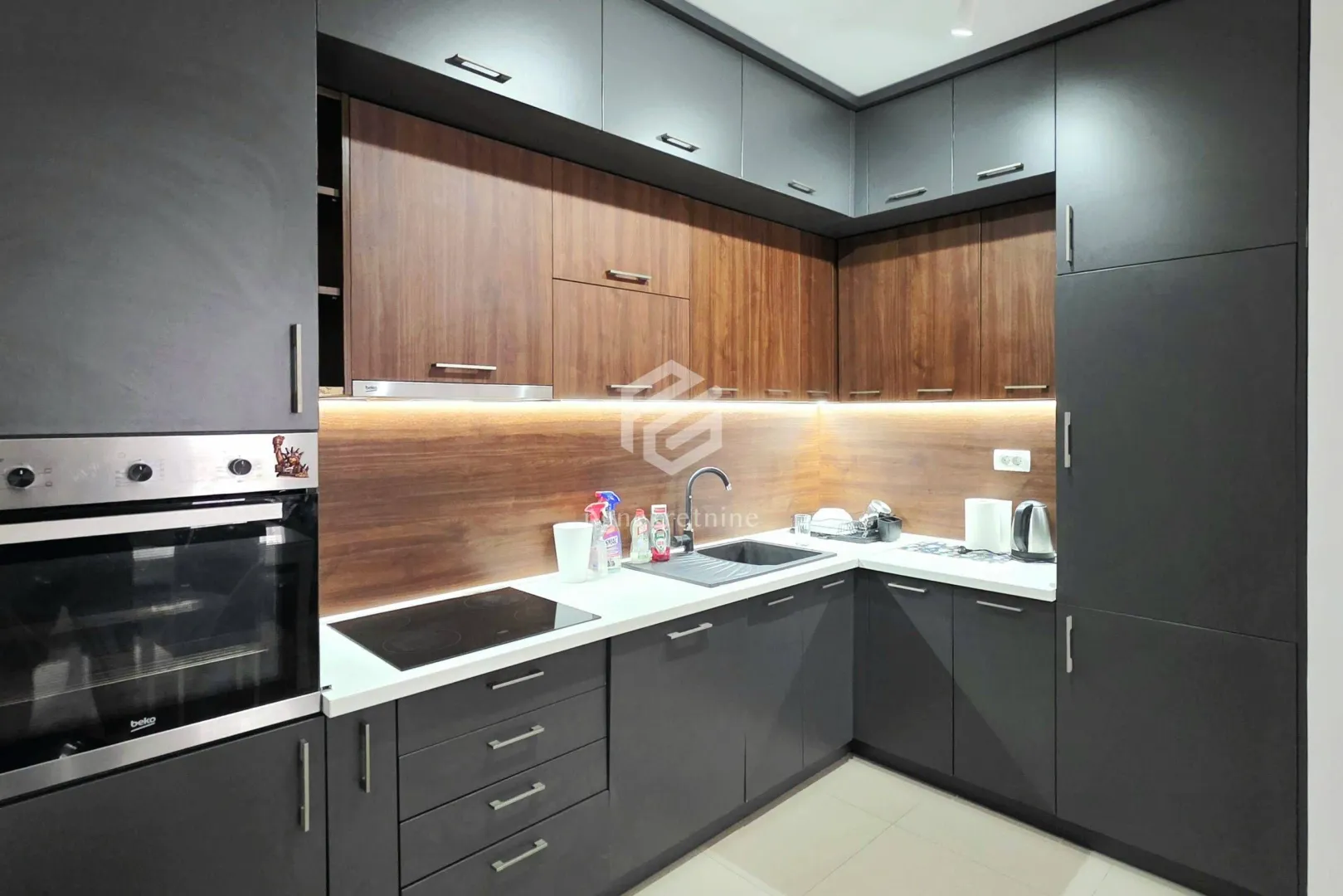 Modern corner kitchen with dark cabinets and wood details.