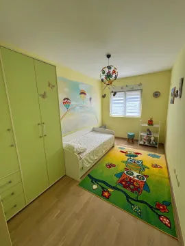 Dječja soba sa zelenim ormarom, krevetom i šarenim tepihom. - image 10