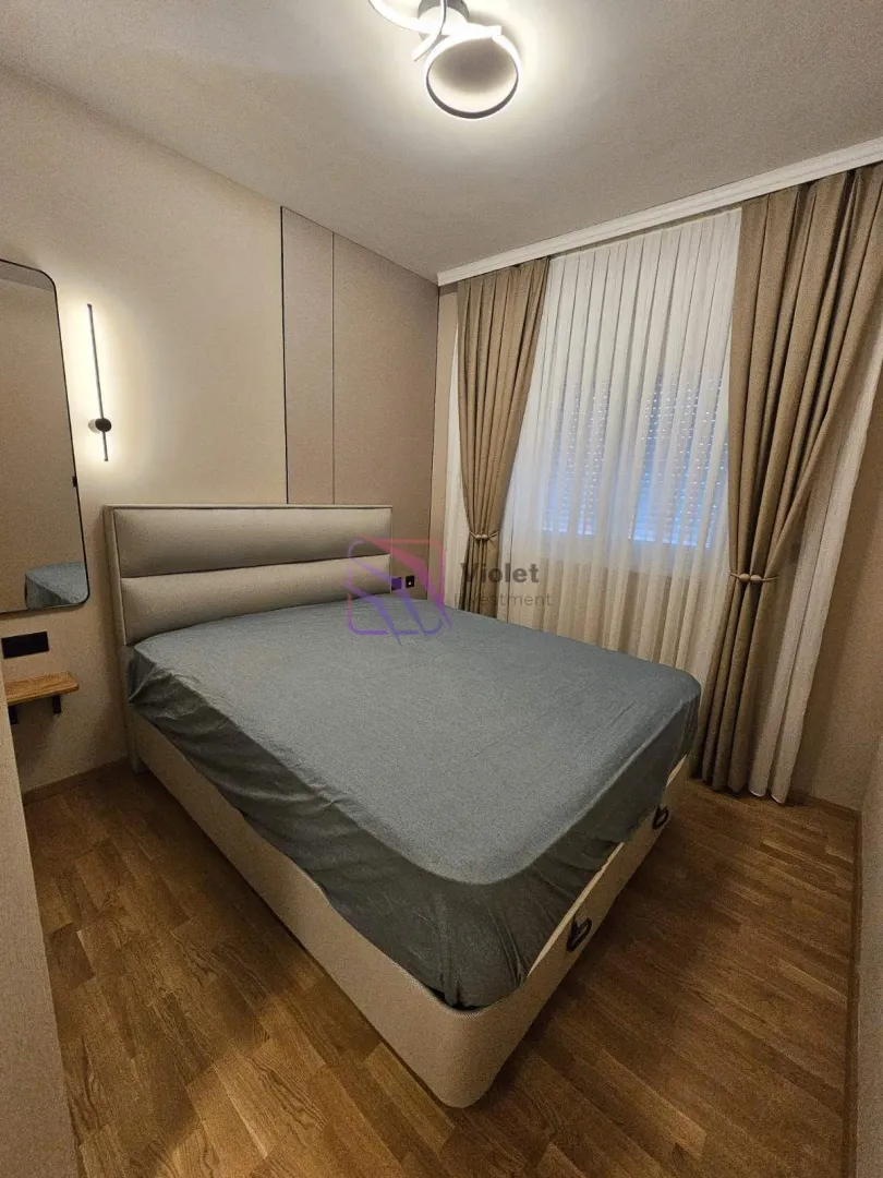 Furnished bedroom with a double bed and a window with curtains.