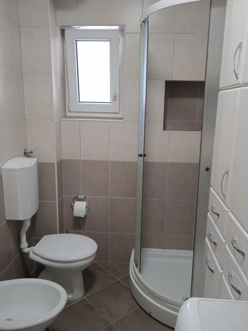 Manje kupatilo sa tuš kabinom, WC šoljom, bideom i ormarićem.