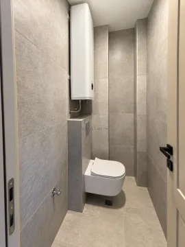 Manje kupatilo obloženo sivim pločicama sa ugradnom šoljom i bojlerom. - image 14