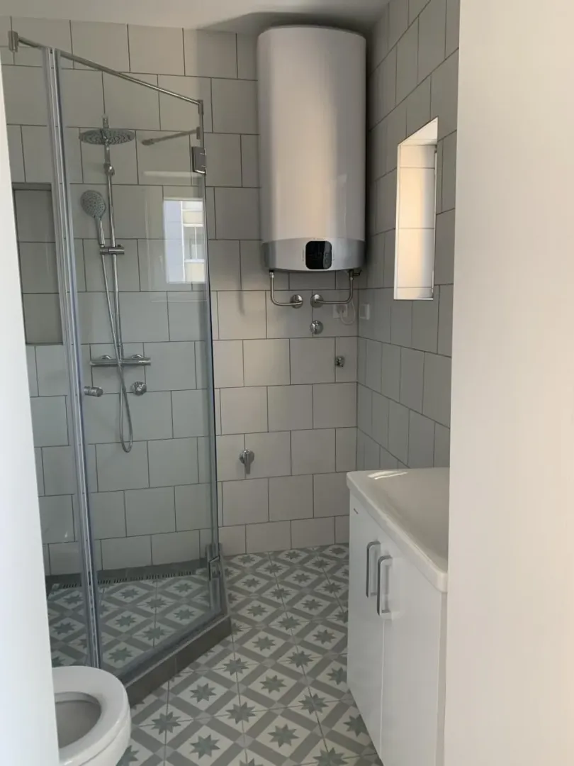 Bathroom with a shower cabin, washbasin, and water heater.