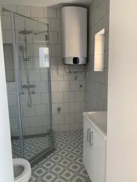 Bathroom with a shower cabin, washbasin, and water heater. - image 10