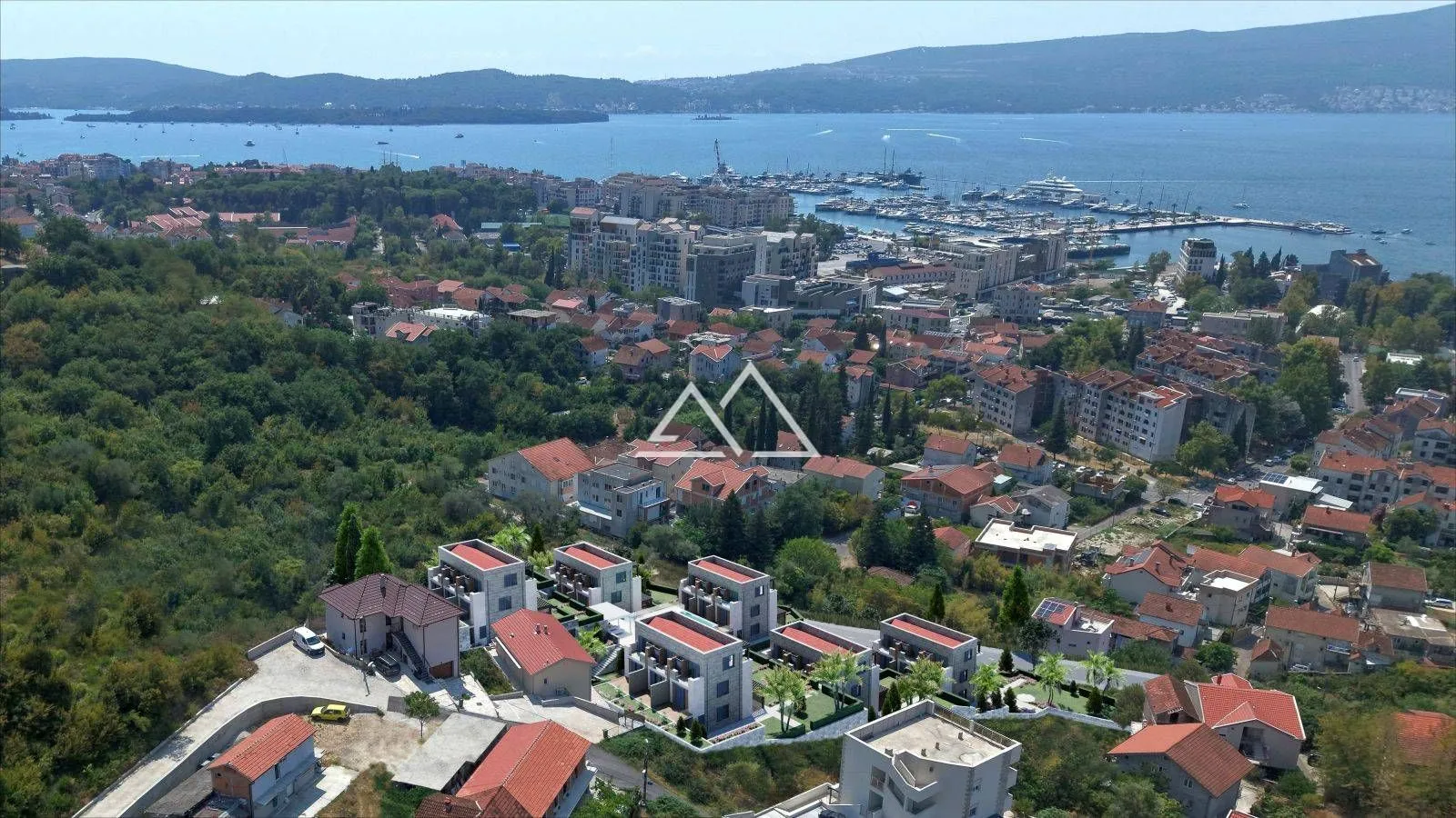 Pogled iz vazduha na naselje i obalu sa marinom u pozadini.