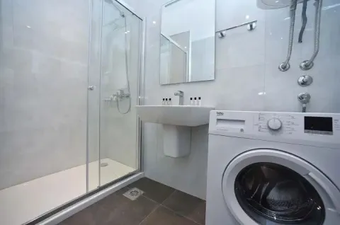 Modern bathroom with a shower cabin, washbasin, and washing machine. - image 2