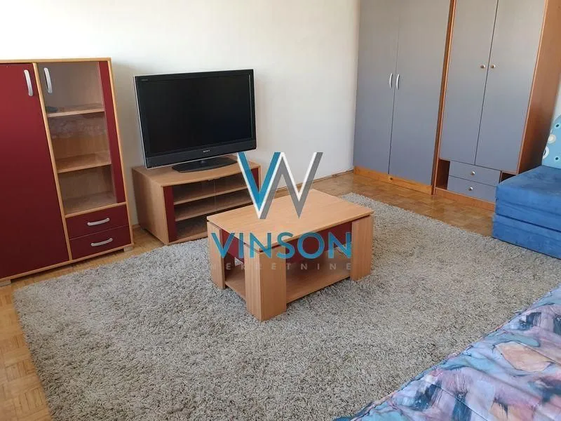 Dnevni boravak sa garniturom, televizorom i drvenim nameštajem.