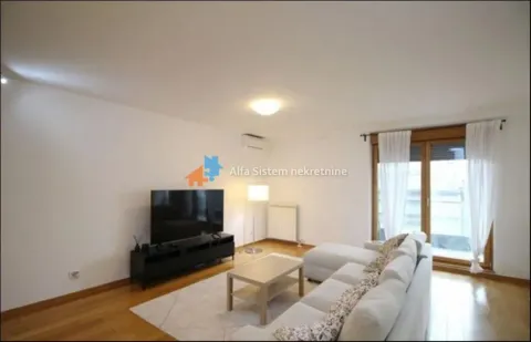 Dnevna soba opremljena ugaonom garniturom, televizorom i izlazom na terasu. - image 6