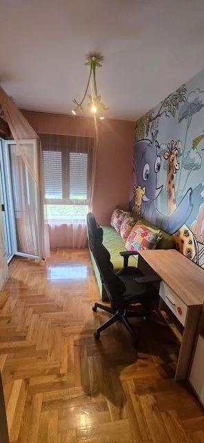 Dječja soba sa krevetom, radnim stolom i tapetom sa životinjskim motivima.