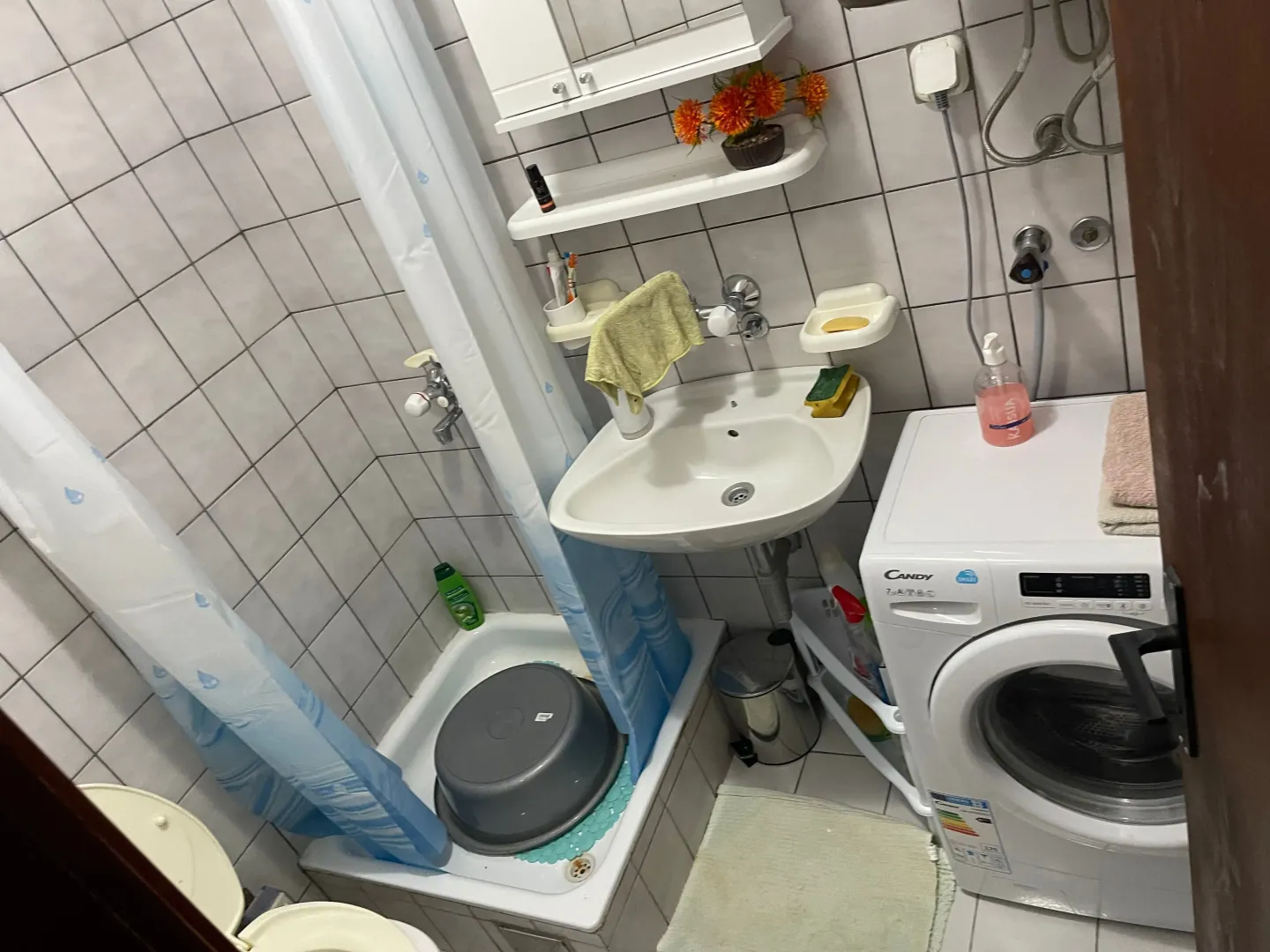 Manje kupatilo sa tuš kabinom, umivaonikom i veš mašinom.