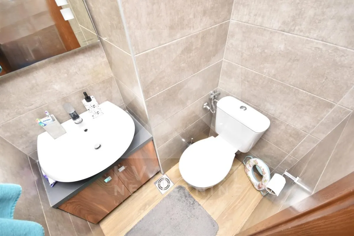 Manje kupatilo obloženo keramičkim pločicama sa umivaonikom i wc šoljom.