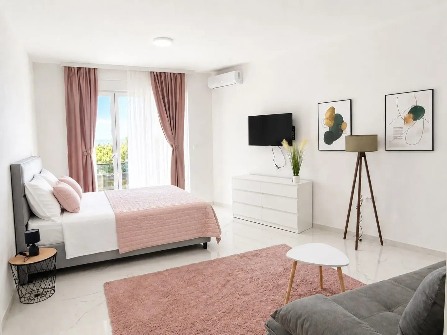 Bright bedroom with a double bed, balcony, and couch.