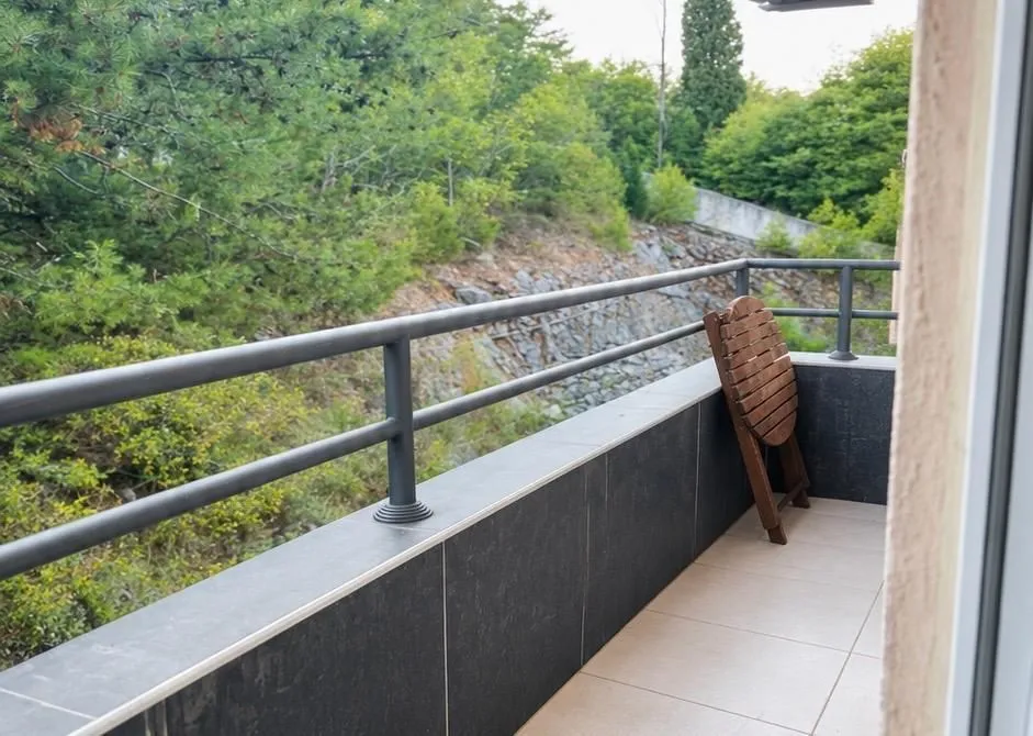 Covered balcony space with a metal railing and a view of greenery.