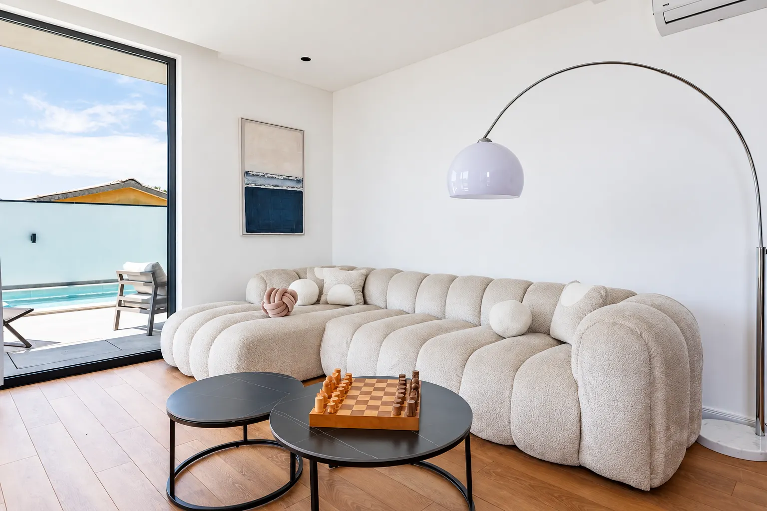 Living room with a comfortable beige sofa, coffee tables and a view of the pool.