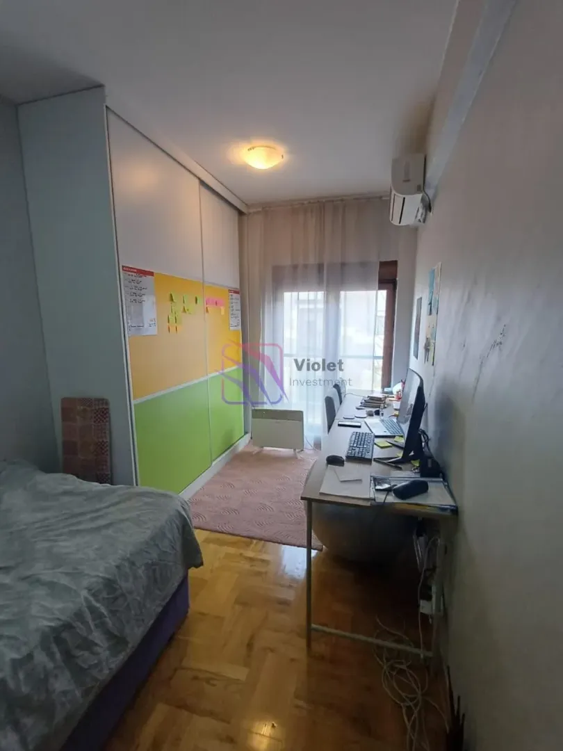Namještena spavaća soba sa krevetom, radnim stolom i velikim ormarom.