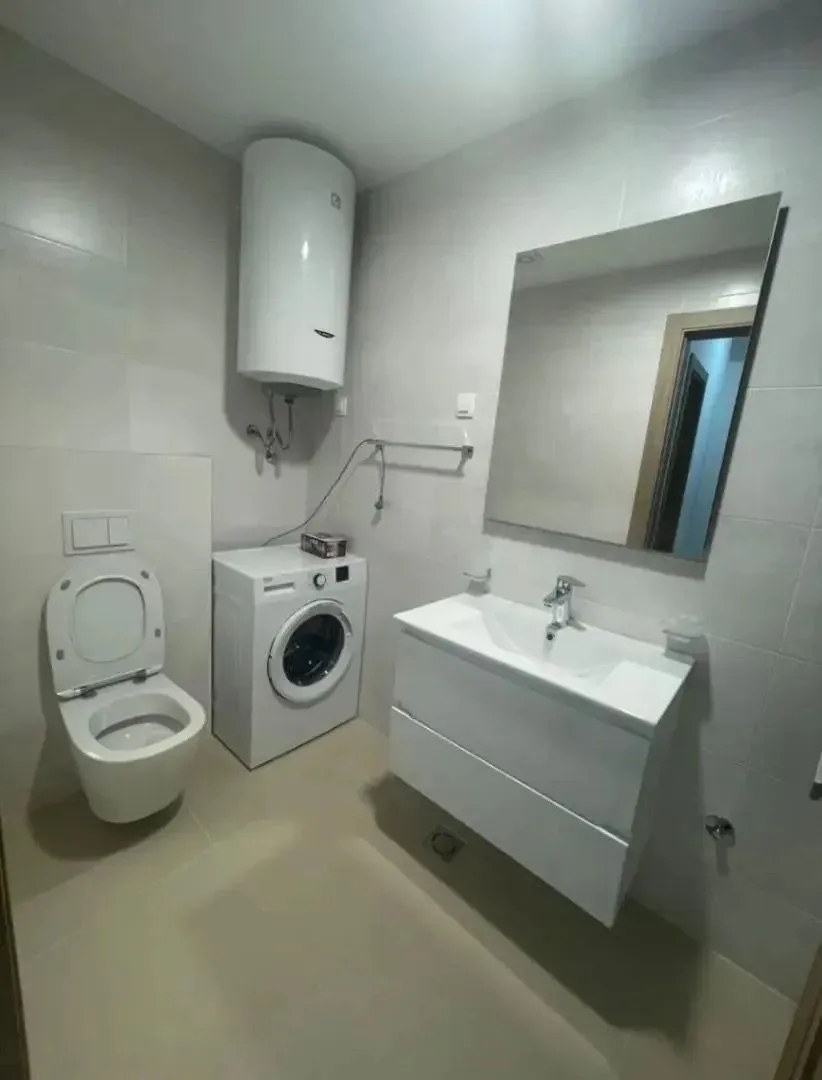 Modern bathroom with a sink, toilet, washing machine, and water heater.