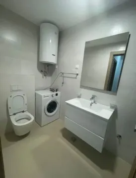 Modern bathroom with a sink, toilet, washing machine, and water heater. - image 8