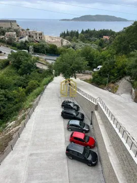 Pogled sa terase na parking prostor i more u daljini. - image 10