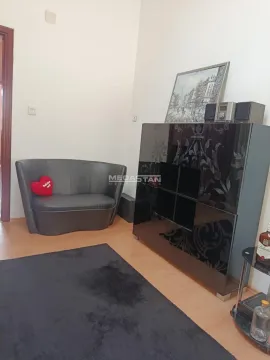 Smaller part of the living room with a black armchair and dresser. - image 8
