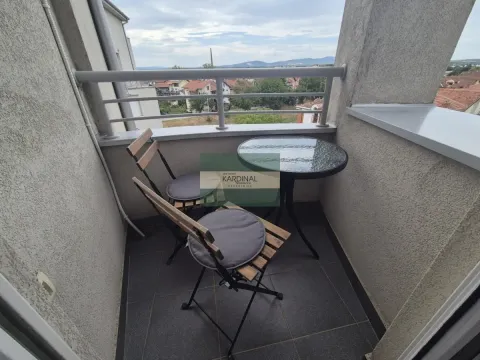 Manji namešteni balkon sa stolom i dve stolice i pogledom na okolinu. - image 19