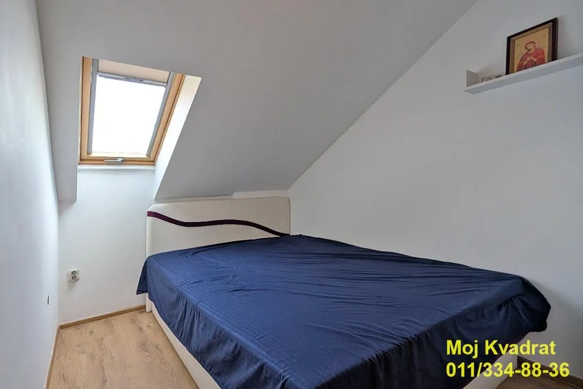 Attic bedroom with a double bed and a roof window.