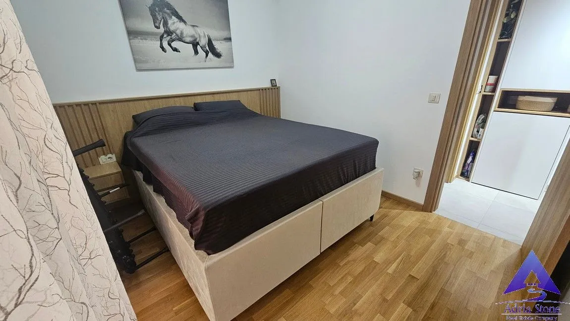 Spavaća soba sa bračnim krevetom, drvenom oblogom na zidu i umjetničkom slikom.