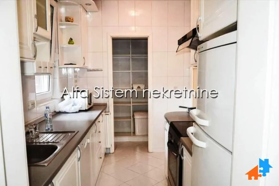 Compact kitchen with white cabinets and a pantry in the back.