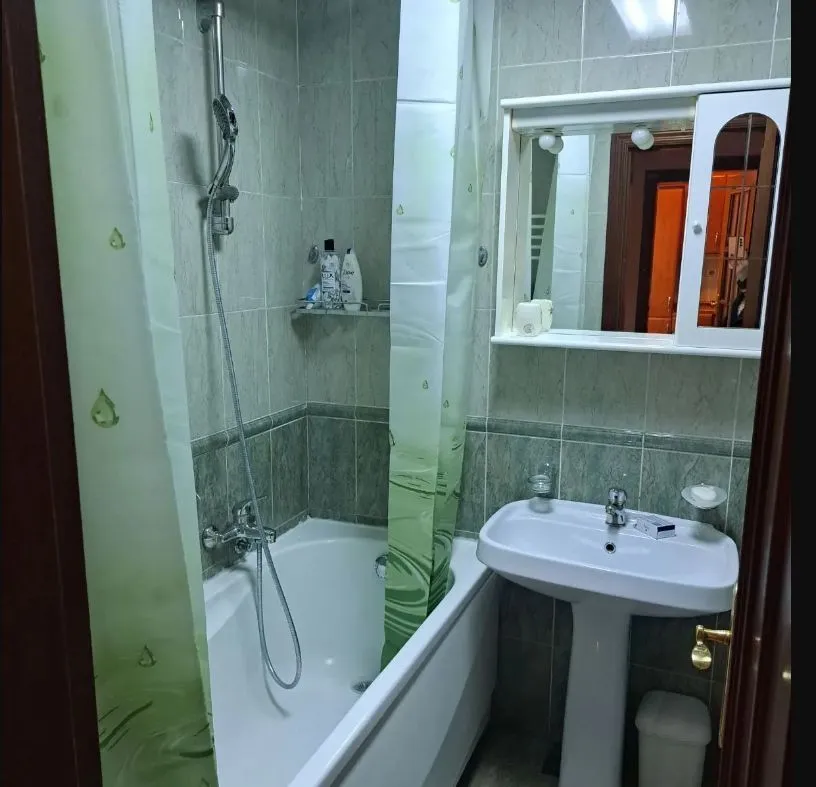 Kupatilo sa kadom, umivaonikom i ormarićem sa ogledalom.